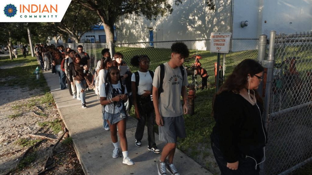 A group of students walking in a line on a sidewalk outside a school