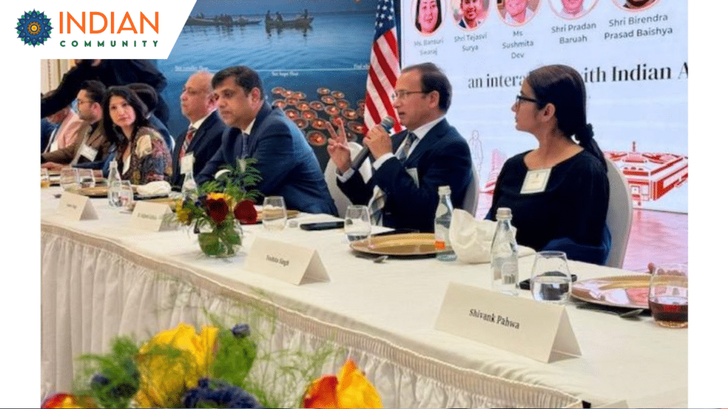 A formal panel discussion is taking place with individuals seated at a long table adorned with nameplates, floral arrangements, and refreshments.