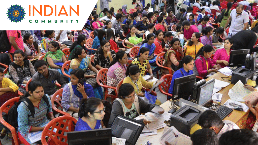 A busy scene of a hall filled with individuals seated in rows of red chairs, many holding documents and engaged in discussions.