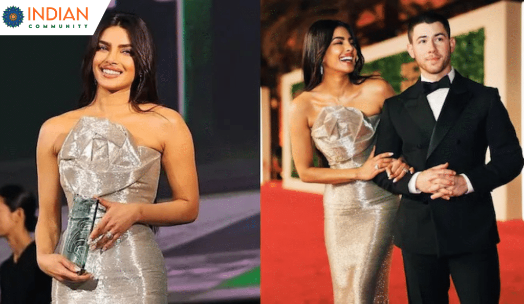 Priyanka Chopra in a silver strapless gown holding an award, accompanied by Nick Jonas in a black tuxedo on a red carpet.