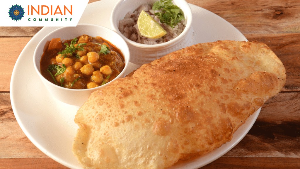 A plate of Delhi Chole Bhature served with pickled onions, green chilies, and a side of tangy chutney.