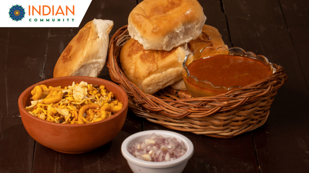 Homemade Pune Misal Pav with a bowl of spicy curry, farsan topping, and pav bread, garnished with fresh coriander and served with a lemon wedge.