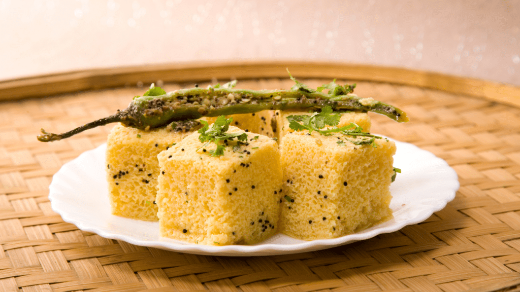 Soft and fluffy Gujarati Dhokla garnished with coriander leaves and grated coconut.