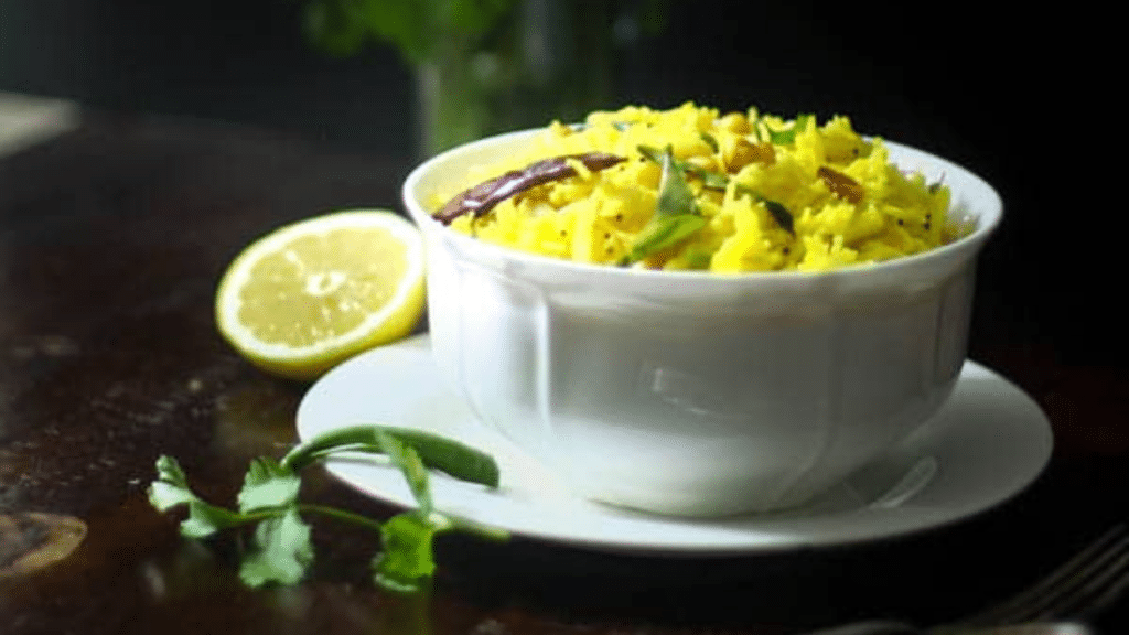 A bowl of lemon rice garnished with coriander leaves and roasted peanuts.