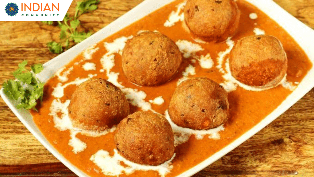 malai Kofta served with soft vegetable dumplings in a rich, spiced gravy, garnished with cilantro and cream