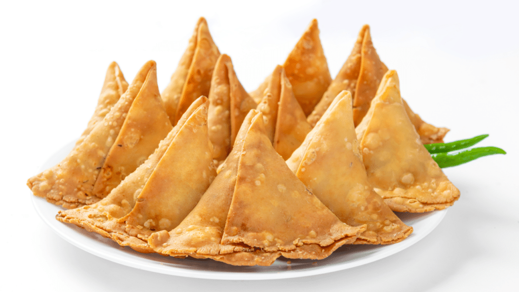 Golden samosas served with mint and tamarind chutney.