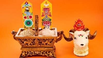 Decorative wooden altar with traditional Indian motifs, colorful ornaments, and a stylized cow figurine displayed against an orange background.